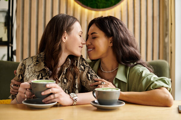 Two women embrace warmly at a cafe table, enjoying each others company and drinks.