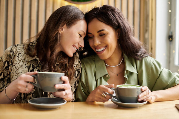 Two women enjoy each others company at a cafe, sharing smiles and warm beverages.