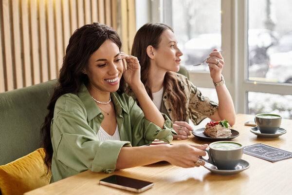 Two women delight in conversation while savoring desserts and drinks at a cozy cafe.