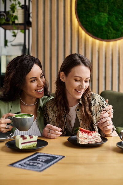 Two women savor delicious desserts and warm drinks in a vibrant cafe, radiating happiness and love.