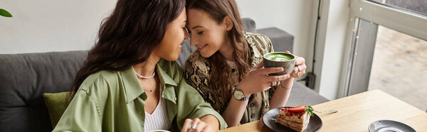 Two women enjoy each others company while sipping drinks and sharing dessert in a warm cafe.