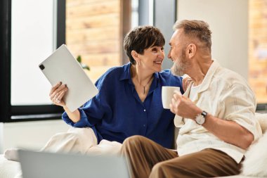 Evli bir çift birlikte rahatlar, gülümsemelerini ve gülüşlerini sıcak oturma odalarında paylaşırlar..