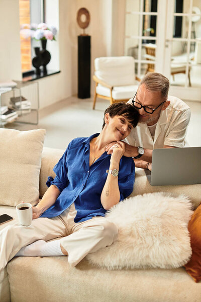 A joyful couple enjoys each other's company while working on a laptop together.