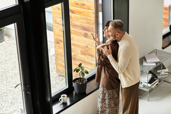 Счастливая пара наслаждается обществом друг друга, глядя за пределы своего теплого дома.