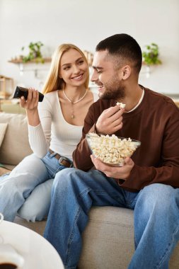 Çift koltukta rahatça oturur, patlamış mısır paylaşır ve birlikte eğlenirken gülümser..