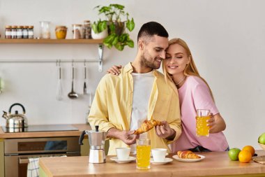 Bir çift, güneşli bir mutfakta, gülücüklerini ve pastalarını paylaşarak, keyifli bir kahvaltıdan zevk alır..