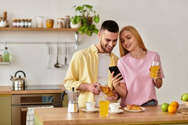 Sevgi dolu bir çift, keyifli bir kahvaltıyı paylaşır. Parlak mutfaklarında hamur işleri ve içkilerin tadını çıkarırlar..