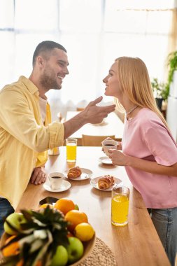 Çift sıcak bir kahvaltı yapar, gülümser ve sıcak mutfak masalarında şefkat gösterir..