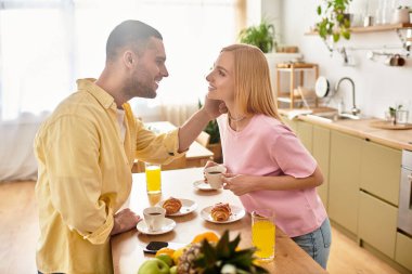 Bir çift, mutfaklarında birbirlerine sevgiyle bakarken lezzetli bir kahvaltıdan zevk alır..