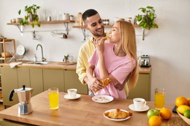 Çift, davetkar mutfaklarında güzel bir kahvaltı yaparken mutlu mesut kucaklaşır..