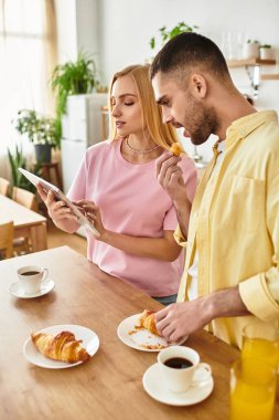 Bir çift evde sıcak kahve ve hamur işleriyle güzel bir kahvaltı yapıyor..