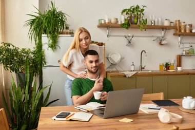 Bir çift evde laptopla ve kahveyle rahatlarken tatlı etkileşimlerini paylaşıyor..