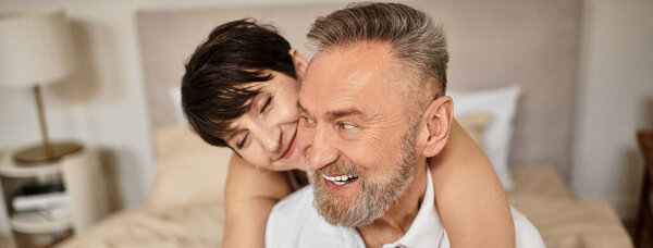 Middle aged couple embraces happily at home, showcasing love and companionship together, banner