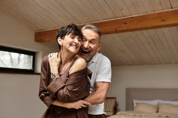 A couple embraces happily, enjoying their time together in a warm and inviting home atmosphere.