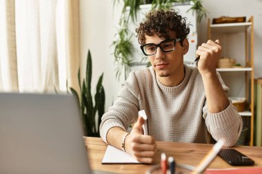 Rahat süveter giyen yakışıklı bir adam ahşap masasında dijital görevlere odaklanıyor..