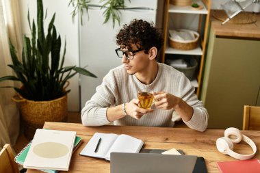 Yakışıklı adam, sıcak ve davetkar bir atmosferde çalışmaya dalmış bir fincan çayla rahatlıyor..