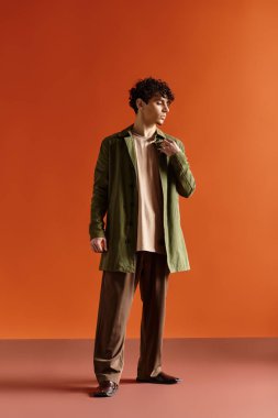 Şık bir genç adam zarif bir elbise içinde kendine güvenerek duruyor ve kendine has tarzını sergiliyor..