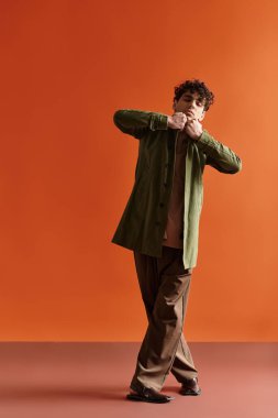 Yakışıklı genç bir adam, moda anlayışını, çarpıcı bir ortamda moda kıyafetiyle sergiliyor..