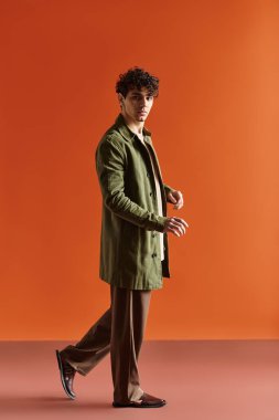 Şık bir genç adam sanatsal bir ortamda şık bir kıyafet içinde poz verir..