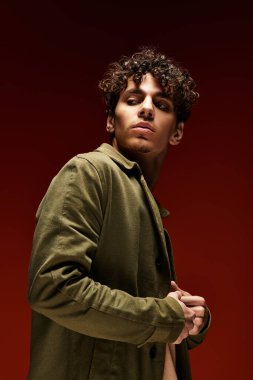 Kıvırcık saçlı şık bir genç sıcak ve canlı bir ortamda rahatça poz verir..