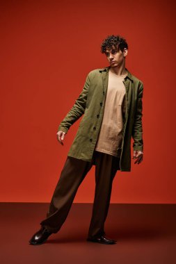 Genç bir adam şık bir kıyafete güvenir. Cüretkar bir ortamda zarafetle durur..