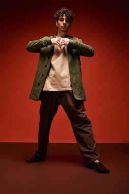 Yakışıklı genç adam kendine güvenerek sanatsal bir ortamda moda kıyafetlerini sergiliyor..