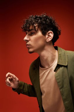 Şık bir adam kendine güvenerek kırmızı arka planda duruyor..