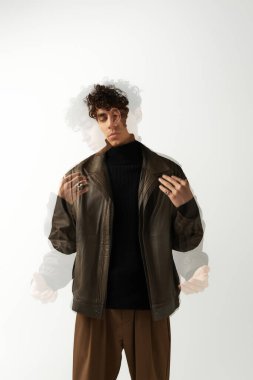 Kendine güveni tam bir adam, minimalist bir stüdyoda şık bir kıyafet içinde yaratıcı bir görünüm sergiliyor..