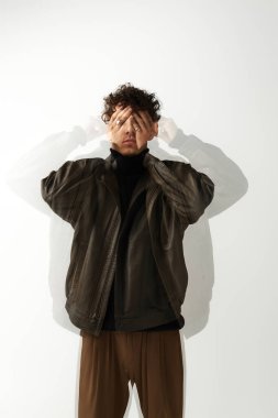 Yakışıklı bir genç adam, eşsiz bir stil sergileyerek, ellerini şakaya vurarak gözlerini kapatıyor..