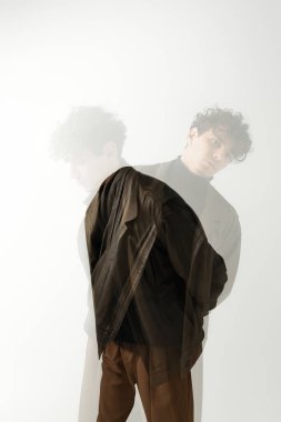 Şık bir genç adam minimalist bir geçmişe karşı güvenle poz verir..