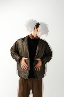 Yakışıklı bir adam yaratıcı bir şekilde minimalist bir ortamda poz verirken modaya uygun bir kıyafet sergiliyor..