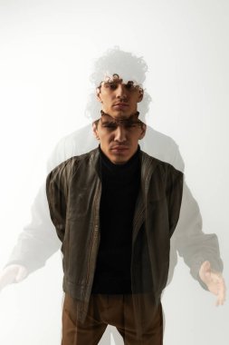 Şık ceketli genç adam dinamik bir çifte teşhircilik sergileyerek özgüvenli bir poz veriyor..