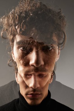 Kıvırcık saçlı yakışıklı genç bir adam şık bir kıyafet giyerken değişik duygular sergiliyor..
