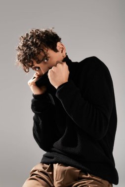 Tarz sahibi genç bir adam siyah kazağını şık bir ortamda düzeltir..