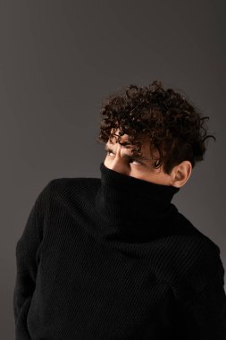 Şık siyah kazaklı genç bir adam kendine güvenen bakışları ve benzersiz bakışlarıyla dikkatleri üzerine çeker..