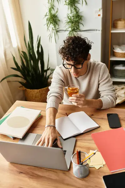 Masasında özenle çalışan, sıcak bir içeceğin tadını çıkaran şık genç bir adama odaklan..