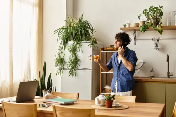 Yakışıklı genç bir adam, bitkilerle dolu modern bir mutfakta telefonda sohbet ediyor..
