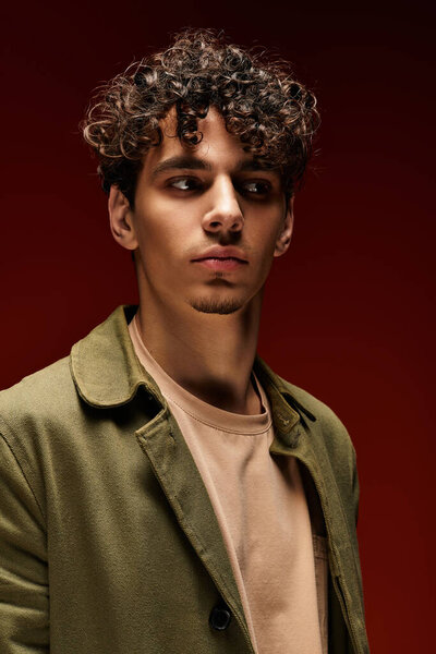 Стильный мужчина с вьющимися волосами выставляет напоказ свою моду в смелой обстановке.