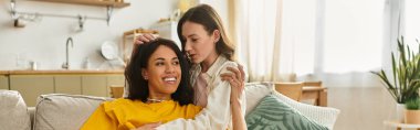 İki kadın evde rahatlarken birbirlerine şefkat gösteriyorlar, birbirlerine eşlik ediyorlar ve gülüyorlar..