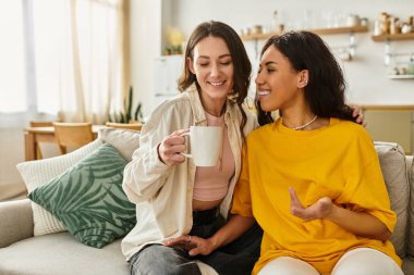 İki kadın rahat bir kanepede içkilerini yudumlarken aynı kahkahayı ve sevgiyi paylaşıyor..