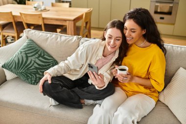 İki kadın, davet odalarında akıllı telefona bakarken aynı kahkahayı ve sevgiyi paylaşıyor..