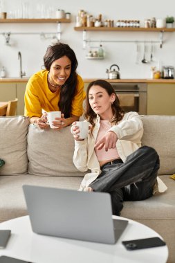 İki kadın kanepede sarılır, sıcak içkileri paylaşır ve birlikte bir şeyler izlerler..
