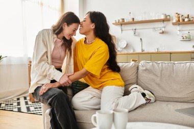 İki kadın sıcak ev çevreleriyle çevrili rahat bir kanepede keyifli, samimi bir anı paylaşıyor..