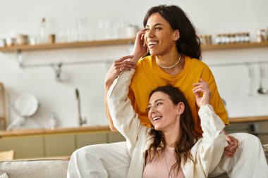 İki kadın sıcak bir anda kucaklaşıyor, gülümsüyor ve evde birbirlerine eşlik ederek eğleniyorlar..