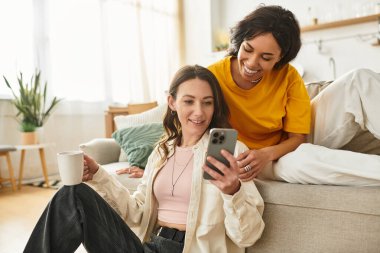 İki kadın gülümseme ve kahkahaları rahat bir odada akıllı bir telefonla dolaşırken paylaşır..