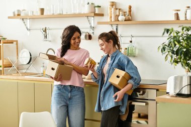 İki kadın eve davet ettikleri kutuları neşeyle açıyor, gülüşlerini ve sevgilerini paylaşıyorlar..