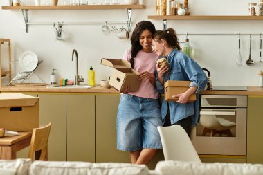 İki kadın, yeni evlerinde sıcak bir atmosfer yaratmak için birlikte kutuları açıyor..