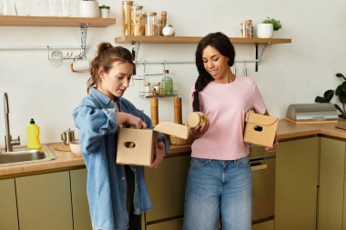 İki kadın, güzel evlerinin mutfağında kutuları açarken keyifli bir anı paylaşıyor..