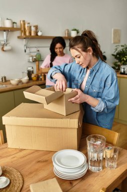 İki kadın mutlu bir şekilde evlerinde kutuları açıyor, rahat ve sevgi dolu bir yer yaratıyorlar..