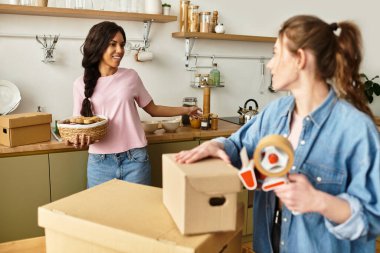 İki kadın yeni mutfaklarında kutuları açarken keyifli bir anı paylaşıyorlar..
